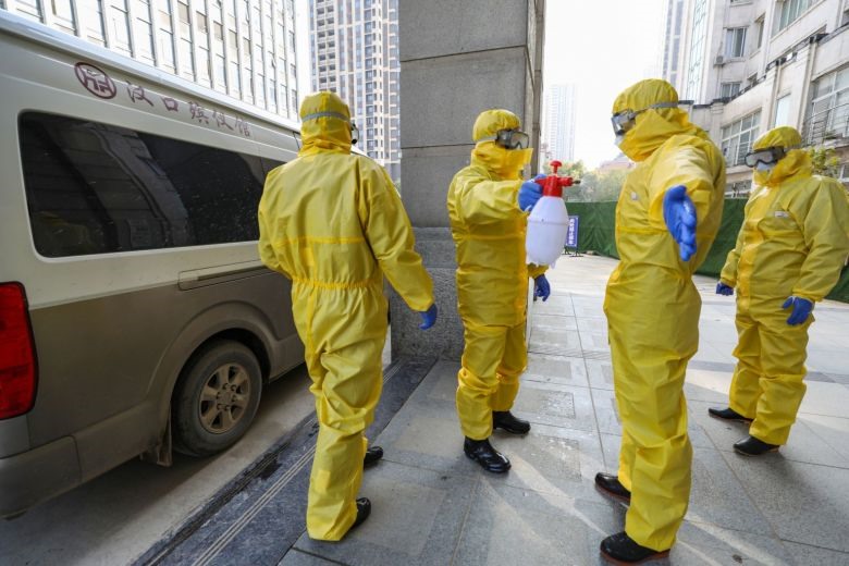 Nhân viên nhà tang lễ trong trang phục bảo vệ giúp đồng nghiệp khử trùng sau khi họ chuyển một thi thể tại bệnh viện trong bối cảnh dịch virus Corona bùng phát ở Vũ Hán, tỉnh Hồ Bắc, Trung Quốc. Ảnh: Reuters.