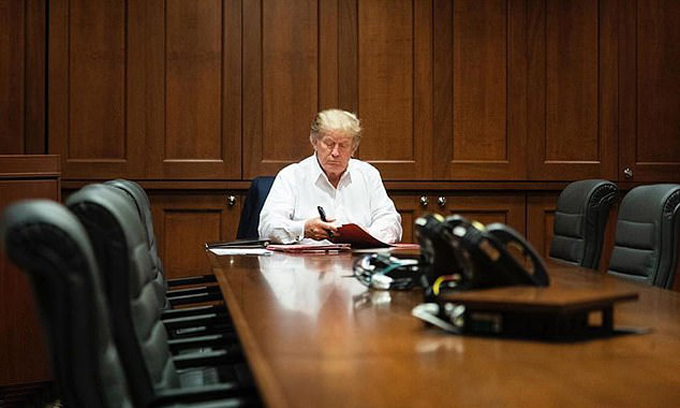 Tổng thống Mỹ Donald Trump ngồi làm việc ở Trung tâm Quân y Walter Reed hôm 3/10. Ảnh: EPA.